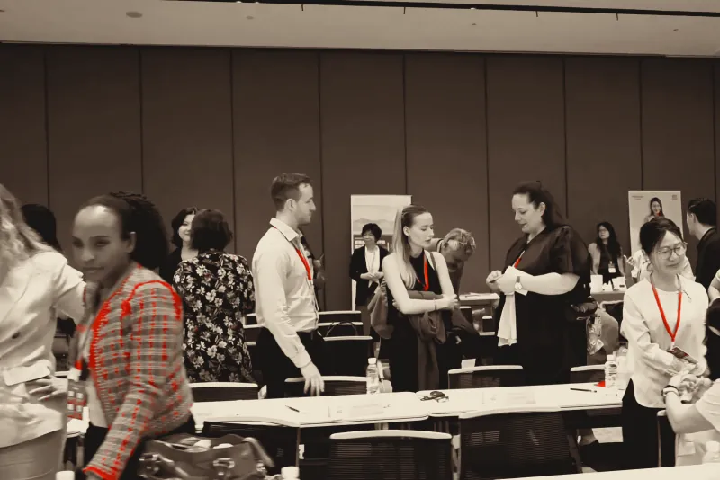 Attendees talking between sessions, red lanyards around their necks.